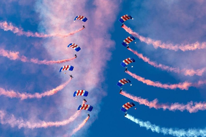 10 people parachuting with red and blue gas coming out of them
